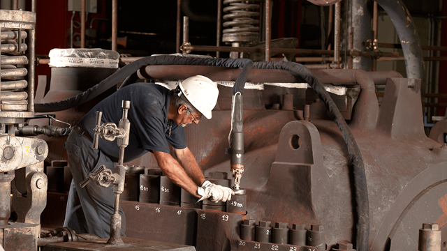Technician applying induction heating for bolt expansion on a large turbine casing