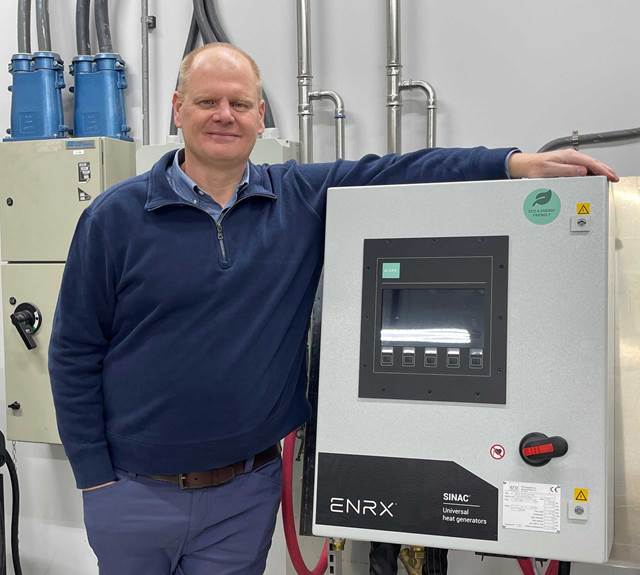 Mark Andrus standing next to wall-mounted ENRX Sinac universal heat generator system which will be used to power bonding application