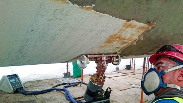 Induction heating system removing protective coating from steel surface during ship maintenance