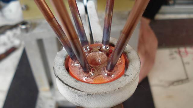 Close-up of induction brazing of a heat distributor with multiple copper tubes being brazed simultaneously inside an  induction coil using ENRX induction heating technology