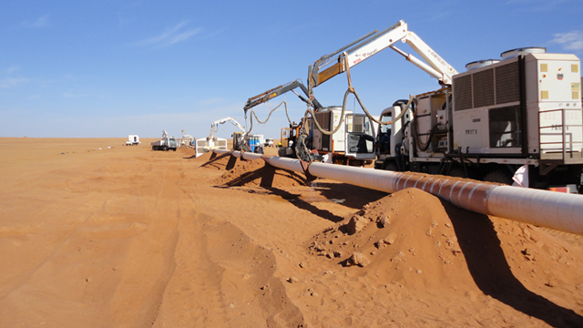Pipeline welding preheating in a desert environment using mobile induction heating units positioned along the pipeline.