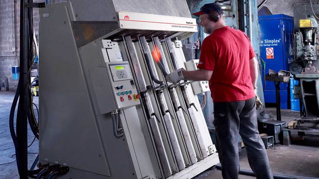 Operator heating steel components in an industrial induction forging system using induction heating