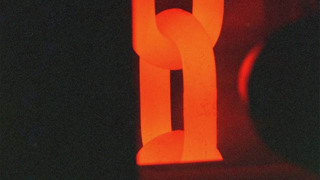 Red-hot steel chain link undergoing induction heat treatment for controlled hardening and strength