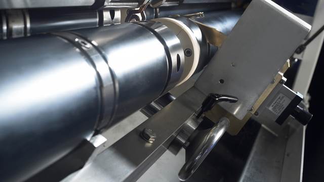 Close-up view of induction tempering equipment applying controlled heat treatment to a metal tube or component.