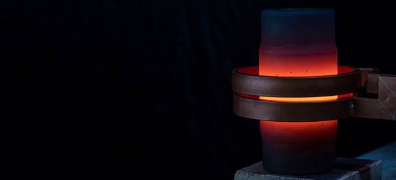 Induction heating of a metal workpiece with a glowing coil demonstrating efficient energy transfer