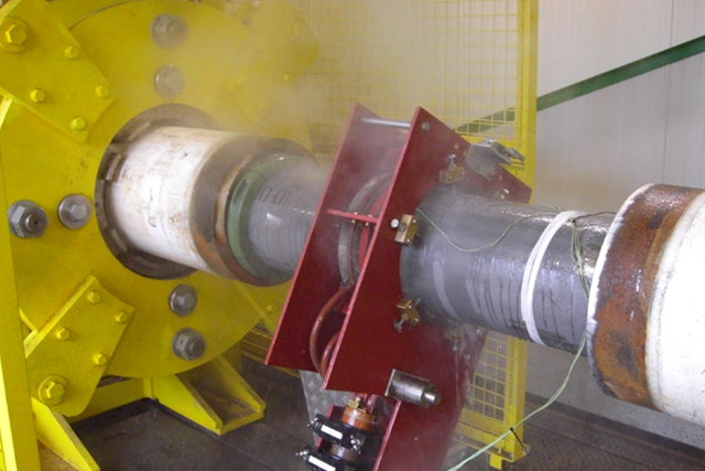 Induction post-heating equipment performing PWHT on a welded pipeline joint, with controlled heating applied around the weld area.
