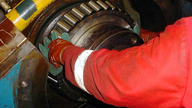 Technician positioning bearing components during ENRX induction preheating for shrink‑fitting