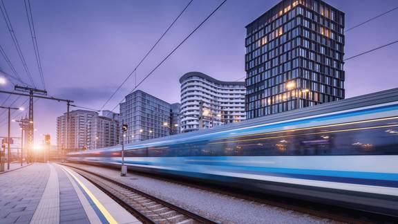 High‑speed train passing through a modern city where ENRX induction heating is used for maintenance of rolling stock and rail components
