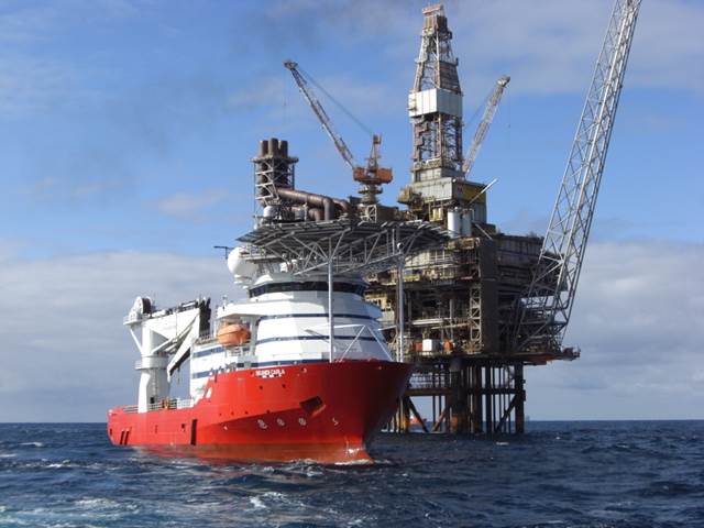 Offshore support vessel positioned beside an oil and gas platform in open sea, illustrating subsea and topside heating operations enabled by ENRX induction technology.