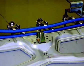 Two-turn full perimeter induction coil mounted on an automotive panel assembly, showing improved flexibility and homogeneous heating compared to older single-edge coils.