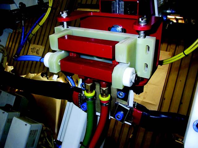 Close-up of ENRX U-Coil® induction bonding system showing dual heating configuration and compliance mechanism for precise, distortion-free automotive panel bonding.