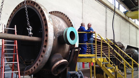 Workers performing boiler tube extraction on a large industrial boiler, a process commonly enhanced by induction heating for safe and efficient tube removal.