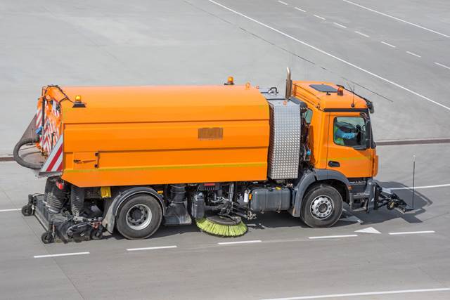 Sweeper electric truck with brushes and vacuum cleaner drives on asphalt