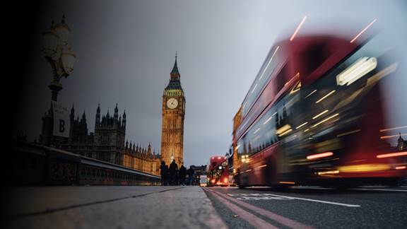 Electric bus driving past Big Ben in London, illustrating urban inductive charging solutions for buses and trucks