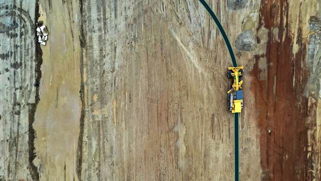 Aerial view of a mining site with heavy machinery following a marked path, illustrating the concept of ENRX dynamic wireless charging for off-road vehicles.