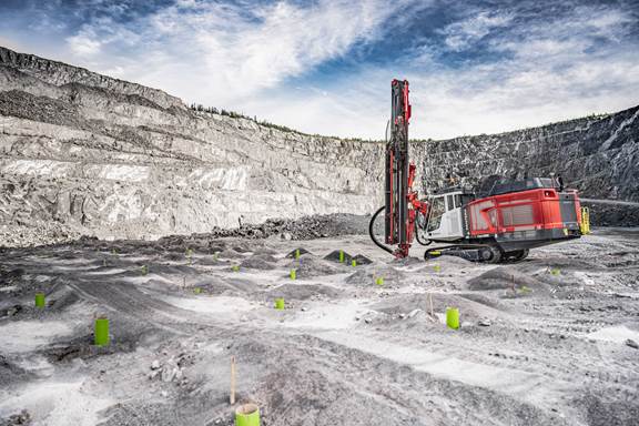Open-pit mining site with drilling machinery prepared for wireless inductive charging of heavy-duty electric mining trucks.