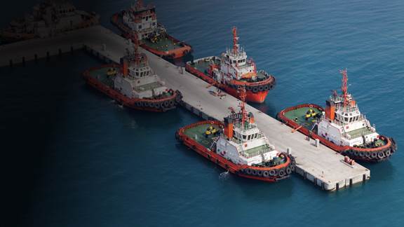 Tugboats docked at a pier illustrating potential for ENRX wireless inductive shore-to-ship charging solutions.
