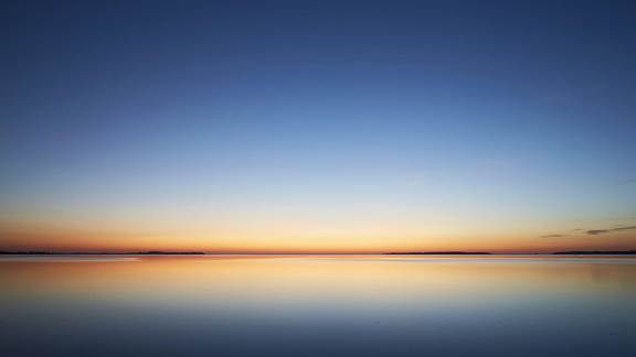 Pôr do sol sereno sobre um lago calmo e refletor, simbolizando um fabrico limpo e ambientalmente responsável com aquecimento por indução na ENRX