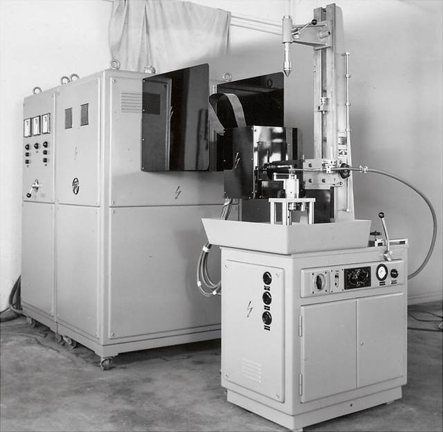 Vintage photograph of the first induction hardening machine developed by Fritz Düsseldorf, showing early industrial heating technology.
