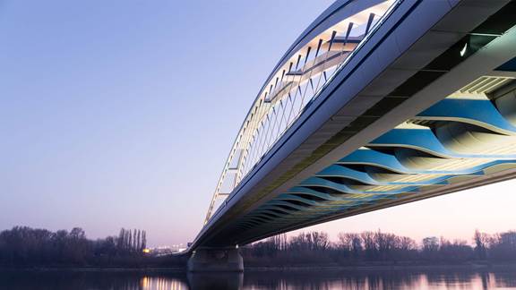Modern arched bridge at dusk representing induction heating for roads and bridges