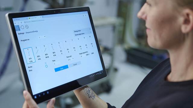 Technician configuring ENRX Minac induction heating settings on tablet interface