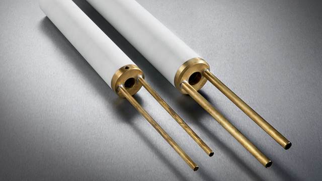 Two ENRX hollow ID scarfing impeders with ceramic bodies and brass fittings, used in induction welding of tubes and pipes