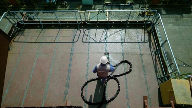 Shipyard worker performing induction deck straightening using an ENRX Terac heating tool on a steel surface.