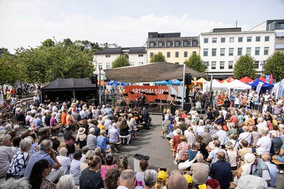 Audience attending an outdoor event at Arendalsuka surrounded by colorful tents and local discussions in Arendal, Norway