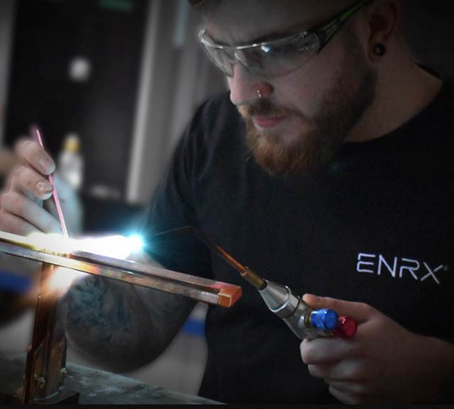 ENRX technician brazing a custom induction heating coil in a specialist coil manufacturing workshop