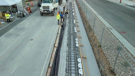 Engineers installing ENRX inductive charging coils for the ASPIRE Electric Roadway test track, demonstrating wireless charging technology for electric vehicles.