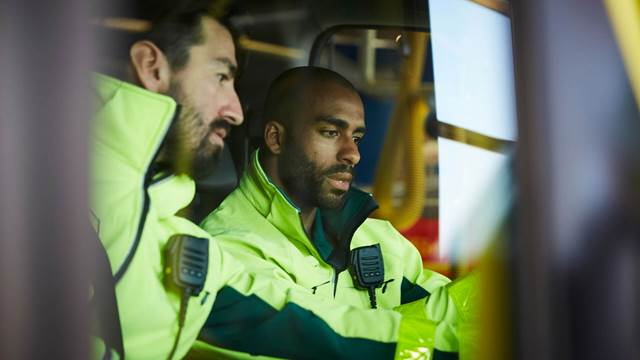 Två ENRX-servicetekniker i varselkläder granskar utrustning på en skärm, vilket representerar servicesupport och reservdelar för induktionsvärmesystem