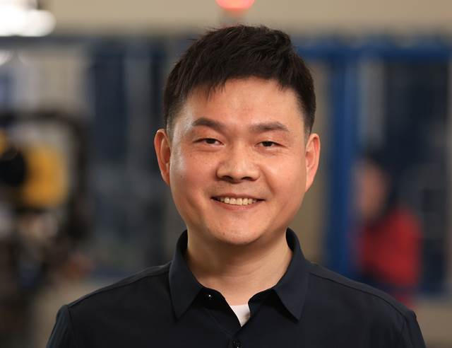 Smiling ENRX team member in an industrial workspace, representing the company’s expertise in induction technology.