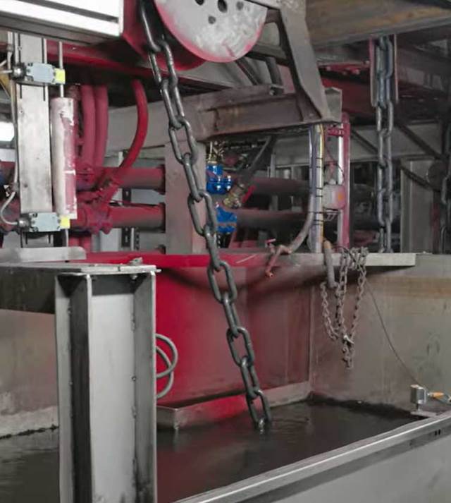 Chains going into cooling water after being hardened by induction heat